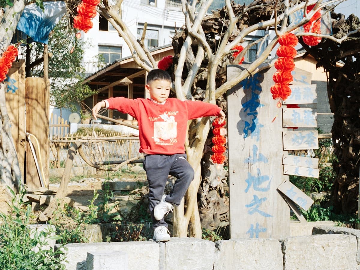 A kid balancing along a wall, arms out, mid-wobble